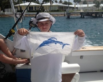 kid on a boat holding blue marlin flags